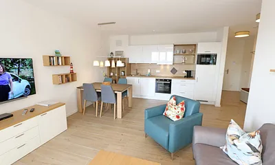 offener Wohn-/ Küchenbereich mit Couchtisch, Sessel, Stehlampe, Sideboard, bequemer Ledercouch, Smart-TV von Loewe mit Blu-Ray-Player und Musik-CD`s