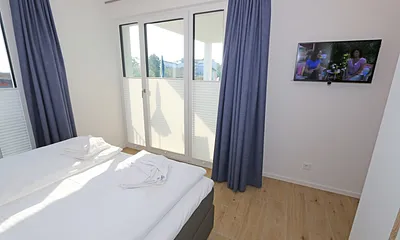 Schlafzimmer mit Boxspringbett (1,80 m x 2,00 m) in Komforthöhe, Nachttischablagen mit Wandleuchten, großzügiger Kleiderschrank und Smart-TV