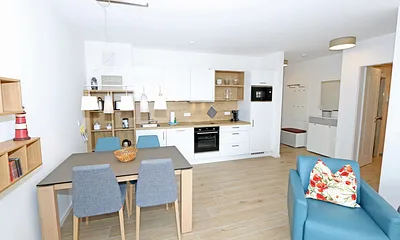 offener Wohn-/ Küchenbereich mit Couchtisch, Sessel, Stehlampe, Sideboard, bequemer Ledercouch, Smart-TV von Loewe mit Blu-Ray-Player und Musik-CD`s