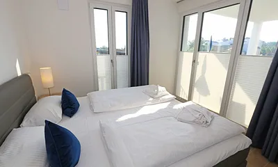 Schlafzimmer mit Boxspringbett (1,80 m x 2,00 m) in Komforthöhe, Nachttischablagen mit Wandleuchten, großzügiger Kleiderschrank und Smart-TV