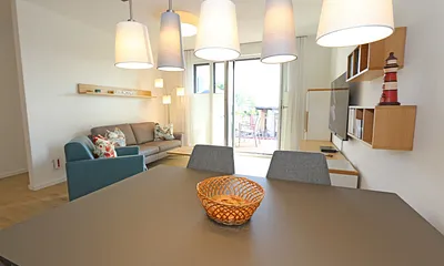 offener Wohn-/ Küchenbereich mit Couchtisch, Sessel, Stehlampe, Sideboard, bequemer Ledercouch, Smart-TV von Loewe mit Blu-Ray-Player und Musik-CD`s