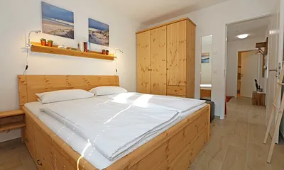 Schlafzimmer mit Doppelbett (1,80 m x 2.00 m), verstellbare Lattenroste, Nachttischablagen, Ganzkörperspiegel, Kleiderablage, geräumiger Kleiderschrank, Smart-TV sowie Verdunklungs-Vorhängen