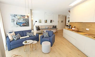 gemütlicher Wohn-/ Essbereich mit hellen Eichenholz Möbeln, Sessel, Couch mit Leselampe, Beistelltische, Stehlampe & 65“ Smart-TV 