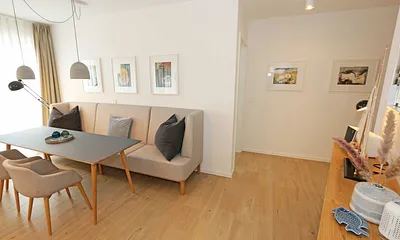 gemütlicher Wohn-/ Essbereich mit hellen Eichenholz Möbeln, Sessel, Couch mit Leselampe, Beistelltische, Stehlampe & 65“ Smart-TV 