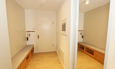 Eingangsbereich mit einer breiten Sitzbank inklusive Schubfächern, Ganzkörperspiegel, Garderobe und einem geräumigen Schrank für Strandutensilien und Koffer