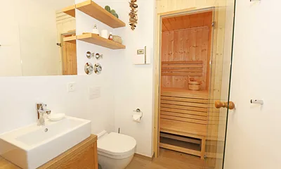 Badezimmer mit Waschtisch inklusiven Schubladen und Ablagefächern, Wandspiegel, WC, Fön,  Kosmetikspiegeln und Sauna