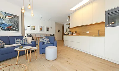 gemütlicher Wohn-/ Essbereich mit hellen Eichenholz Möbeln, Sessel, Couch mit Leselampe, Beistelltische, Stehlampe & 65“ Smart-TV 