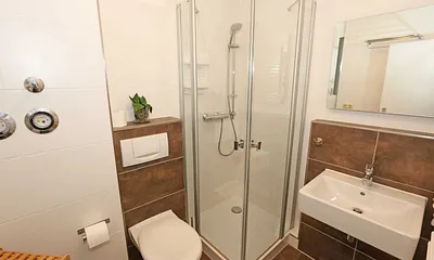 Badezimmer mit ebenerdiger Dusche, Waschplatz, WC, Handtuchheizkörper, Kosmetikspiegel und Fön