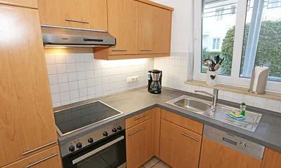 separate Küchenzeile mit Cerankochfeld, Dunstabzugshaube, Backofen, Geschirrspüler, Kühlschrank mit Eisfach, Kaffeemaschine, Wasserkocher, Toaster und diversen Küchenutensilien