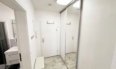 freundlicher Eingangsbereich mit großem Spiegel und Schuhablage mit Sitzbank