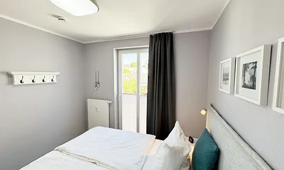 Schlafzimmer mit Boxspringbett, Nachttischablagen sowie Verdunkelungsvorhang