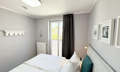 Schlafzimmer mit Boxspringbett, Nachttischablagen sowie Verdunkelungsvorhang