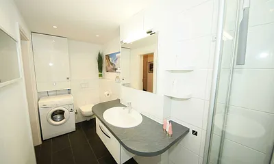 Badezimmer mit Waschmaschine, Waschbecken und WC