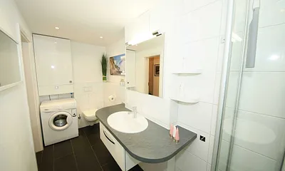 Badezimmer mit Waschmaschine, Waschbecken und WC