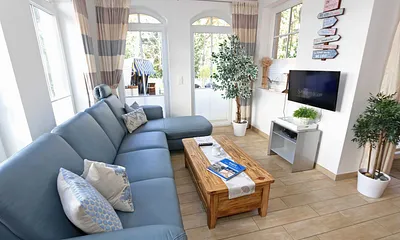 gemütlicher Wohnbereich mit Ecksofa, Glasvitrine mit Büchern und Gesellschaftsspielen, Leselampe, Smart-TV mit Blu Ray-Player, DAB Radio und CD-Player