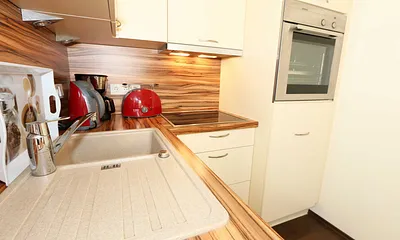 integrierte Küchenzeile mit Geschirrspüler, Keramikspüle, Ceranfeld, Backofen, Kühlschrank mit Gefrierfach und diversen Küchenutensilien