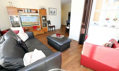 gemütliche Sitzecke bestehend aus Ledercouch (ausklappbar 1,40 m x 2,00 m mit Lattenrost und Matratze) und zwei Sesseln, Leselampe, Smart-TV.