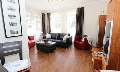 gemütliche Sitzecke bestehend aus Ledercouch (ausklappbar 1,40 m x 2,00 m mit Lattenrost und Matratze) und zwei Sesseln, Leselampe, Smart-TV.