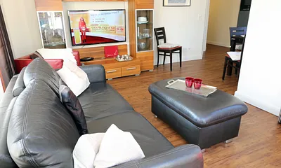 gemütliche Sitzecke bestehend aus Ledercouch (ausklappbar 1,40 m x 2,00 m mit Lattenrost und Matratze) und zwei Sesseln, Leselampe, Smart-TV.