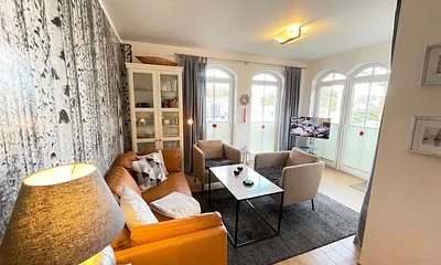 Wohnzimmer mit gemütlicher Sitzecke, Leselampe, Smart-TV, DVD-Player und Telefon