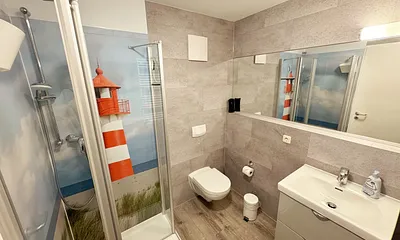 innenliegendes Badezimmer mit WC, Dusche, Waschtisch mit Unterschrank, Fön, Kosmetikspiegel, großem Wandspiegel, Handtuchheizkörper und einem Ablageregal