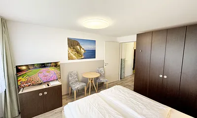 Wohn/Schlafbereich mit 43 Zoll Smart TV,Doppelbett mit Einzelmatratzen (1,80 m x 2,00 m), Nachttischablagen mit Leselampen, geräumiger Kleiderschrank mit Safe, Sideboard mit Mini-Stereoanlage