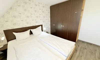 Schlafzimmer mit Doppelbett ( 2 x 0,90 m x 2,00 m ), Nachttischablagen mit Leselampen, 17 Zoll LED-TV, Kleiderschrank mit Safe, Sideboard, Verdunklungsgardinen sowie Insektenschutzgitter