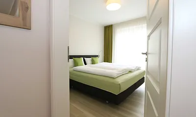 Schlafzimmer mit großem Schwebetürenschrank, bequemen Boxspringbett von Hülsta (1,80 m x 2,00 m, durchgehender Topper), Nachttischablagen und Leselampen