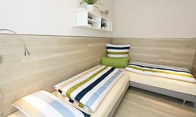 Schlafzimmer mit zwei übereckstehenden Betten (0,80 m x 2,00 m), Leselampen, diversen Ablagemöglichkeiten und zwei kleinen Schränken