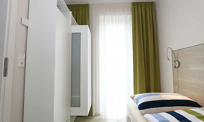 Schlafzimmer mit zwei übereckstehenden Betten (0,80 m x 2,00 m), Leselampen, diversen Ablagemöglichkeiten und zwei kleinen Schränken