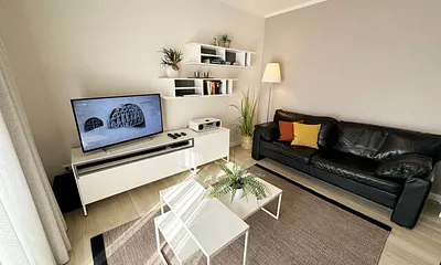 Wohnbereich mit modernen weißen Hülsta Möbeln, ein gemütliches Ledersofa, zwei Sessel, zwei Couchtischen, Stehlampen, DAB Radio mit CD-Player und Bluetooth, Smart-TV mit Soundbar & Blu-Ray Player