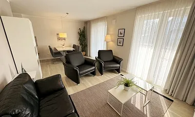 Wohnbereich mit modernen weißen Hülsta Möbeln, ein gemütliches Ledersofa, zwei Sessel, zwei Couchtischen, Stehlampen, DAB Radio mit CD-Player und Bluetooth, Smart-TV mit Soundbar & Blu-Ray Player