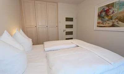 Schlafzimmer  im Landhausstil mit großem Doppelbett (1,60 m x 2,00 m), 5-Zonen-Federkern-Matratzen, verstellbare Lattenroste, Nackenkissen, Nachttischablagen und geräumigen Einbauschrank