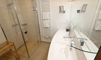 Badezimmer mit Regendusche, großzügigem Doppelwaschtisch, großem Spiegel, Kosmetikspiegel, Handtuchtrockner und Fön