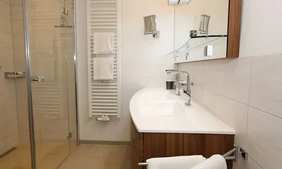 Badezimmer mit Regendusche, großzügigem Doppelwaschtisch, großem Spiegel, Kosmetikspiegel, Handtuchtrockner und Fön