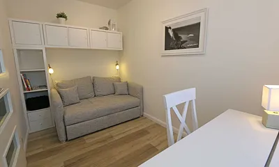 Schlafzimmer mit Funktionssofa (ausziehbare Liegefläche von 1,40 m x 2,00 m), umrahmt von Hängeschränke sowie einem Schreibtisch