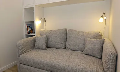 Schlafzimmer mit Funktionssofa (ausziehbare Liegefläche von 1,40 m x 2,00 m), umrahmt von Hängeschränke sowie einem Schreibtisch