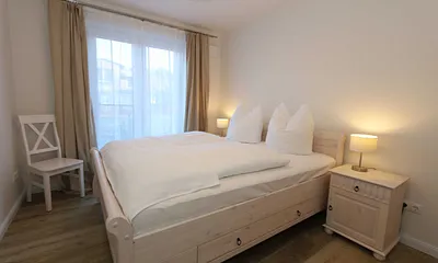 Schlafzimmer  im Landhausstil mit großem Doppelbett (1,60 m x 2,00 m), 5-Zonen-Federkern-Matratzen, verstellbare Lattenroste, Nackenkissen, Nachttischablagen und geräumigen Einbauschrank