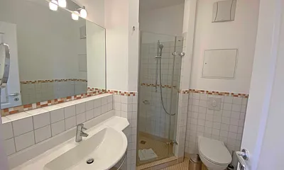 Badezimmer mit Anti-Rutsch-Fliesen, Waschtisch, gemauerte Eckdusche mit hochwertigen Armaturen, WC und beheizbarer Design-Handtuchhalter