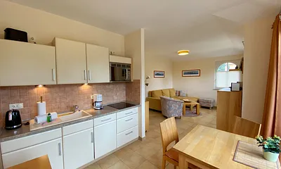 angrenzende Küchenzeile mit Keramikspüle, 3-Zonen-Glaskeramik-Kochfeld, Kühlschrank mit Gefrierfach, Geschirrspüler, Mikrowellen-Dunstabzugs-Kombination, Kaffeemaschine, Wasserkocher und Toaster