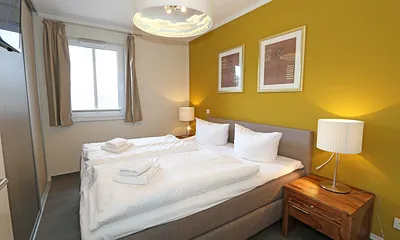 Schlafzimmer mit einem Boxspringbett (1,80 m x 2,00 m), Smart-TV, Nachttischschränken und einen Kleiderschrank