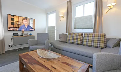 offener Wohnbereich mit gemütlicher Couch, Couchtisch, 2 Leselampen (integriert in den Wandleuchten bei der Couch), Smart-TV, Blu-Ray Player sowie eine Mini-Stereo-Anlage von Sonoro 