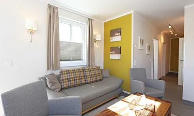 offener Wohnbereich mit gemütlicher Couch, Couchtisch, 2 Leselampen (integriert in den Wandleuchten bei der Couch), Smart-TV, Blu-Ray Player sowie eine Mini-Stereo-Anlage von Sonoro 