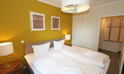 Schlafzimmer mit einem Boxspringbett (1,80 m x 2,00 m), Smart-TV, Nachttischschränken und einen Kleiderschrank