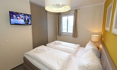Schlafzimmer mit einem Boxspringbett (1,80 m x 2,00 m), Smart-TV, Nachttischschränken und einen Kleiderschrank