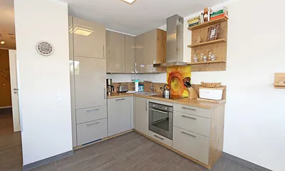 Küchenzeile mit Induktionsfeld, Backofen, Geschirrspüler, Kühlschrank mit Gefrierfach, Kaffeemaschine, Wasserkocher, Toaster und diversen Küchenutensilien