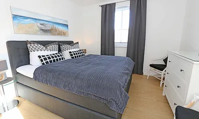 Schlafzimmer mit bequemem Boxspringbett (durchgehenden Topper 1,80 m x 2,00 m) in Komforthöhe, Nachttischablagen mit Nachttischleuchten, Radio-Wecker, Flachbild- TV, Kleiderschrank und Kommode