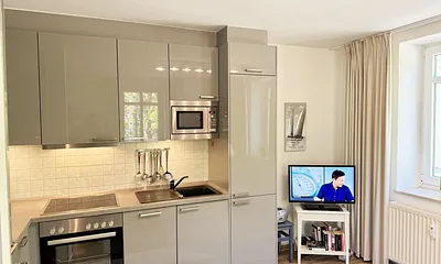 Küchenzeile mit Geschirrspüler, Backofen, 4-Zonen-Ceranfeld, Kühlschrank mit Eisfach, Kaffeemaschine, Mikrowelle, Toaster, Wasserkocher und diversen Küchenutensilien