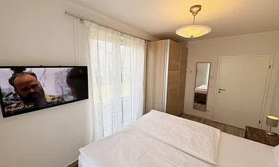 Schlafzimmer mit Doppelbett (2x 0,90 m x 2,00 m) in Komforthöhe (60cm) und zwei 7-Zonenkaltschaummatratzen,Nachttischablagen,Kleiderschrank,Wandspiegel und 40 Zoll LED - Flachbild TV