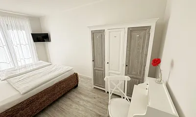 Schlafzimmer mit großem Doppelbett (2x 1,00 m x 2,00 m) in Komforthöhe, verstellbare Lattenroste, Nachttische, Kleiderschrank, Sekretär und Smart-TV mit Sat-Fernsehen